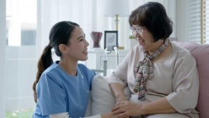 An older adult unpacks family photos with a visiting loved one in a bright, home-like room.